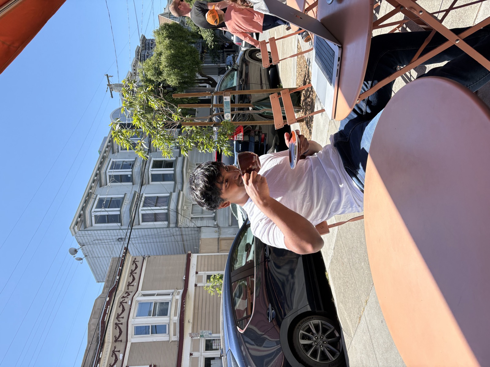 Akshay having coffee on a sunny street in San Francisco