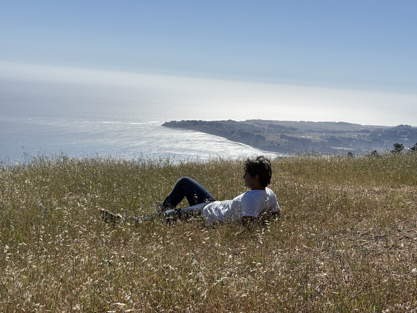 Akshay lying in the grass on Mount Tam, looking out at the ocean